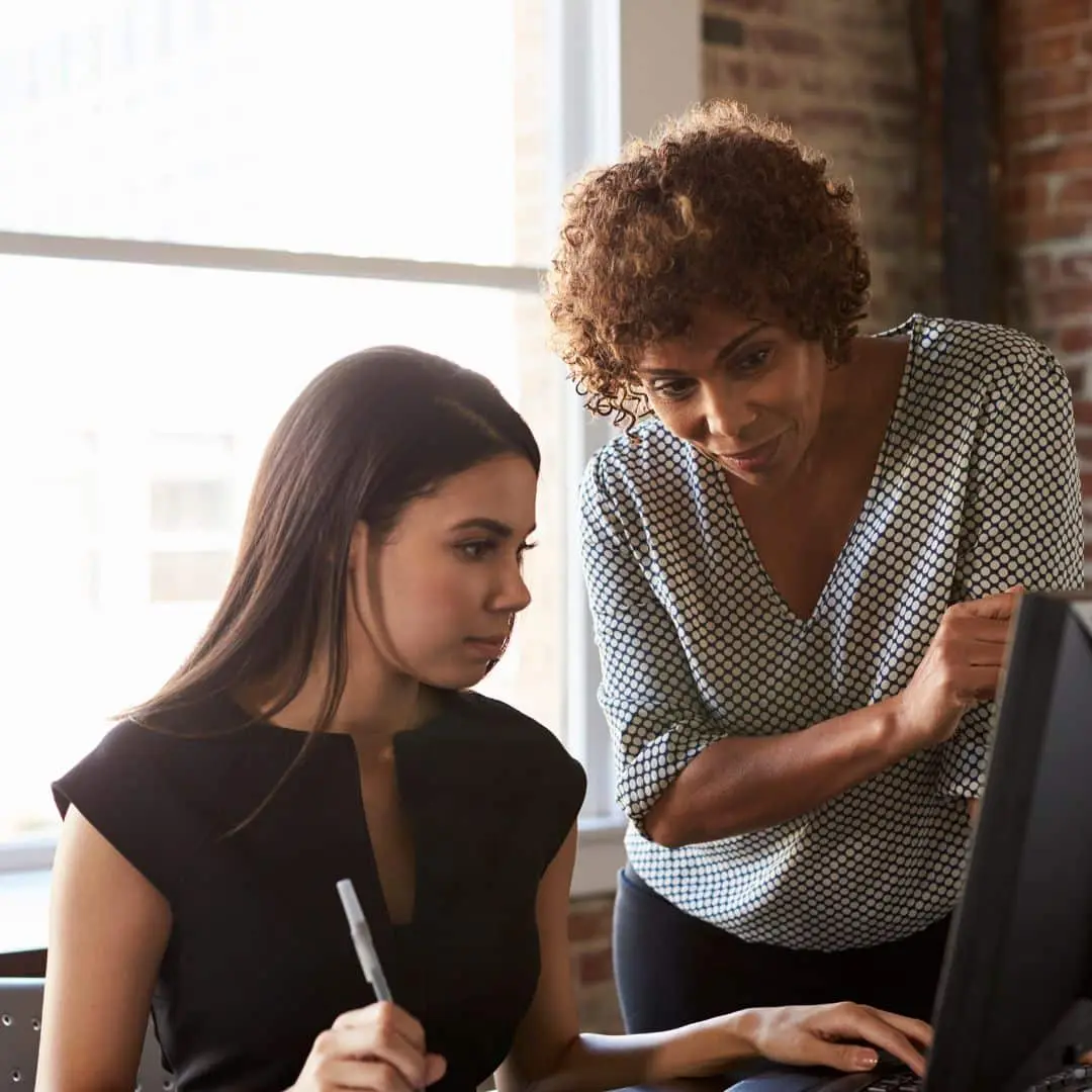 A manager supporting a team member at a workstation